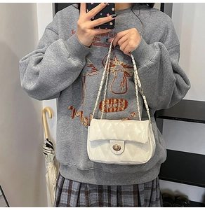 Detailed view of white quilted crossbody bag with metal twist lock and chain strap