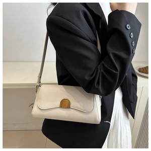 Detail of a minimalist cream white shoulder bag worn with a stylish black blazer