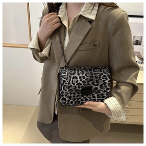 Chic leopard print crossbody bag with black metal buckle shown on a model in a blazer