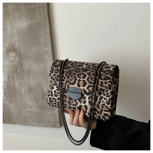 Close-up of leopard print crossbody bag with black metal chain and matte shield buckle