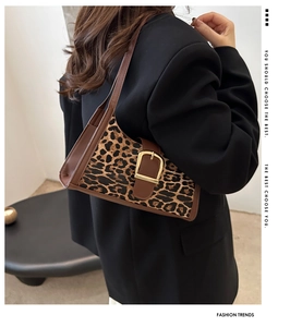 Dettaglio borsa a spalla vintage leopardata con fibbia dorata su un blazer nero elegante