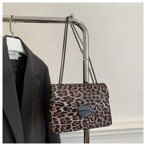 Detail of leopard print chain shoulder bag hanging on a rack beside a grey blazer