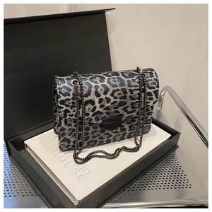 Close-up of blue and black leopard print crossbody bag with metallic chain and buckle