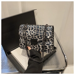 Detail of leopard print flap bag with dark metal chain and shield clasp closure