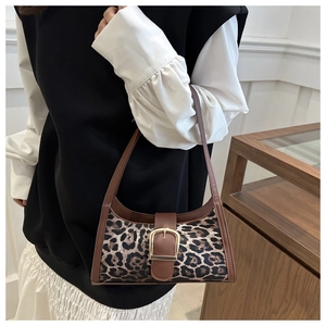 Dettaglio della borsa leopardata con finiture in pelle marrone e fibbia dorata decorativa