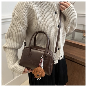 Detail of brown PU leather shoulder bag with embossed logo and teddy dog plush charm
