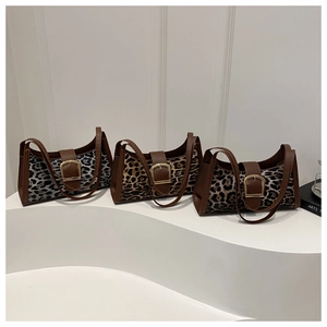 Three leopard print shoulder bags in grey, gold, and brown with leather trim on white stand