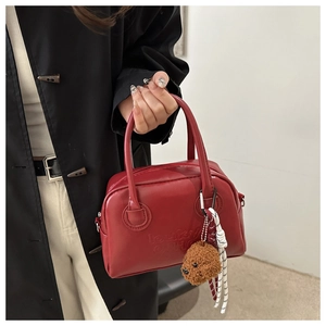 Macro detail of red leather bag with embossed Lucky lettering and a brown puppy charm