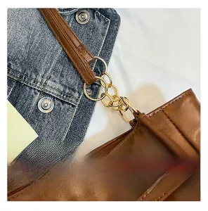 Detail of brown oil-wax leather strap connected by three golden metal rings on a tote bag