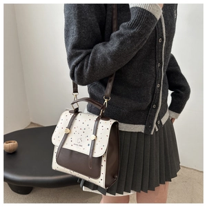 Detail showing the Amity 1986 logo and rabbit emblem on the cream polka dot backpack flap