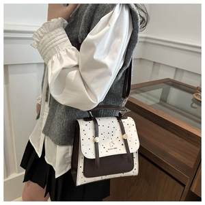 Polka dot crossbody bag with brown straps shown on a model in a warm indoor setting