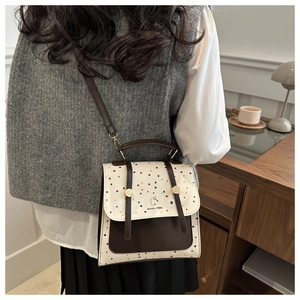 Close-up of retro crossbody bag with colorful dots and leather details on a model