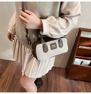 Detail of vintage canvas crossbody bag with brown leather trim and gold metal logo