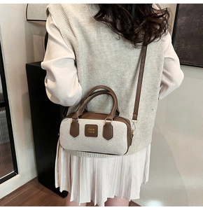 Close-up of a vintage-style canvas and brown leather bowling bag worn as a crossbody