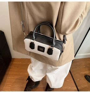 Detailed look at a mini Boston bag in white canvas and black leather on a model outfit