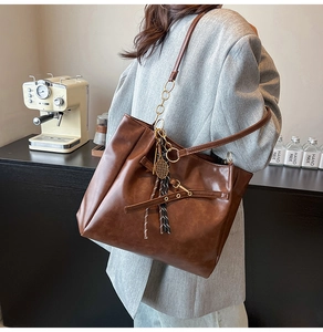 Detail of vintage oil wax leather tote bag with tennis racket charm and bow detail