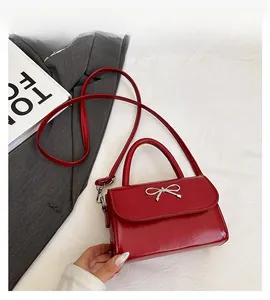 Detail of red patent leather mini bag with silver metal bow and top handle