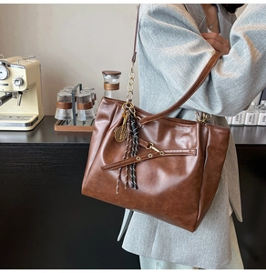 Detail of vintage oil wax leather tote bag with unique metal tennis racket charm