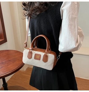 Detail view of canvas and leather Boston bag with brand logo in cozy café setting