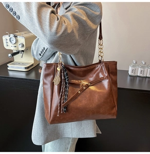 Detail of vintage brown tote bag with metal chain strap and tennis racket charm