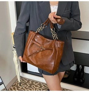 Detail of vintage brown tote bag with metal chain strap and decorative rivets