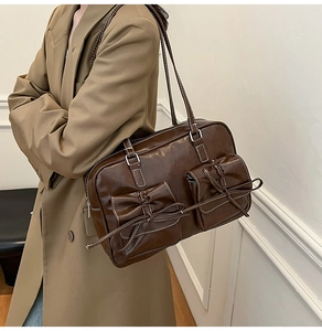 Detail of dark brown retro shoulder bag featuring bow accents and contrast stitching