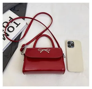 Top view of red patent leather mini bag with silver bow detail and phone for size comparison