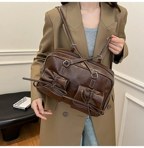 Detail of dark brown PU leather shoulder bag featuring vintage bow pockets and white stitching