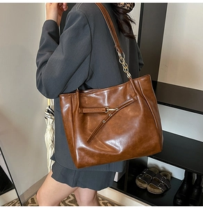 Detail of vintage brown oil wax leather tote bag with metal chain strap and buckle