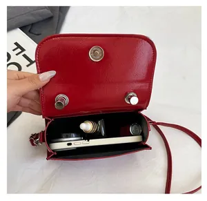 Interior view showing the large capacity of a red glossy crossbody bag with a phone and lipstick