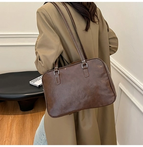 Detail view of deep brown leather bag with white contrast stitching and silver hardware