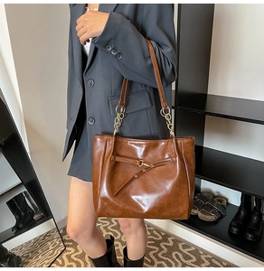 Detail of vintage brown oil wax leather tote featuring gold chain strap and buckle