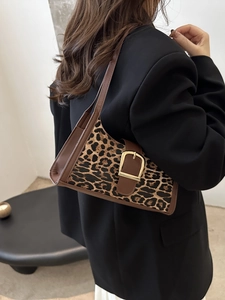 Chic leopard print underarm bag with gold buckle on a stylish model's shoulder