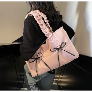 Vue arrière d'un mannequin portant un sac cabas rose avec des nœuds noirs dans un escalier