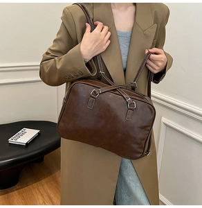 Detail of dark brown retro leather bag with contrast stitching and silver metal hardware
