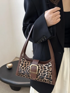 Vintage leopard print shoulder bag with brown leather trim and gold buckle on a model