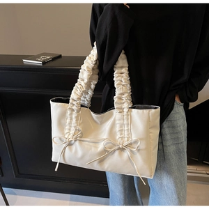 Détail de la poignée à volants et des nœuds décoratifs sur ce sac fourre-tout crème