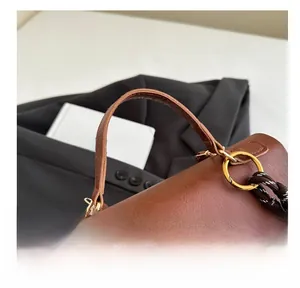 Detail der braunen Handtasche mit Goldringen und Webriemen auf einem Anzug