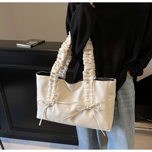 Gros plan sur la poignée plissée et le ruban d'un sac cabas en nylon crème chic