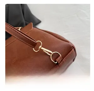 Nahaufnahme des goldenen Karabinerverschlusses und des braunen Lederriemens am Rucksack