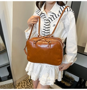 Detail of a brown vintage square bag featuring glossy PU leather and dual shoulder straps