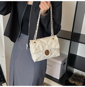 Dettaglio borsa a tracolla trapuntata beige con fibbia dorata e tracolla a catena