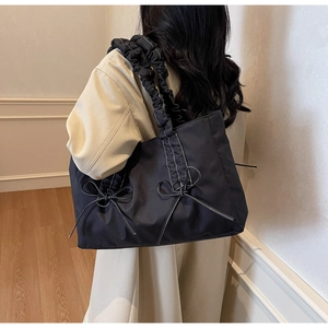 Détail du sac cabas noir avec surpiqûres blanches et bandoulière à volants