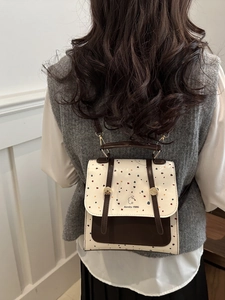 Polka dot backpack in vintage style featuring brown faux leather straps and brand logo
