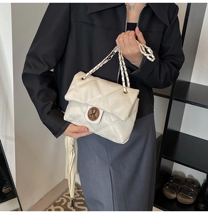 Dettaglio borsa trapuntata beige con elegante chiusura rotonda in metallo goffrato