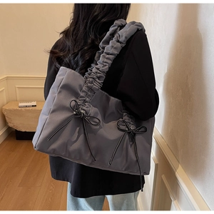 Détail du sac cabas bleu-gris en nylon avec bretelles plissées et petits nœuds noirs