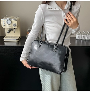 Detail of black faux leather tote with white contrast stitching and silver metal buckles