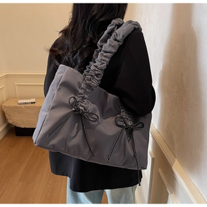 Détail du sac cabas bleu-gris avec bandoulière plissée et nœuds décoratifs noirs élégants