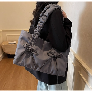 Détail du sac cabas bleu gris avec bandoulière plissée et petits nœuds noirs décoratifs