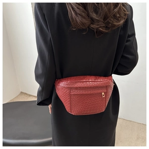 Détail d'un sac de poitrine en cuir tressé rouge avec fermetures éclair dorées